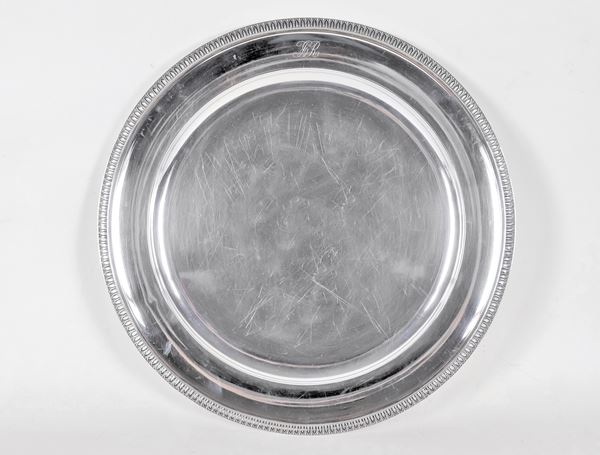 Large round silver serving plate, with chiselled edge with neoclassical palmettes and engraved monogram, gr. 1250