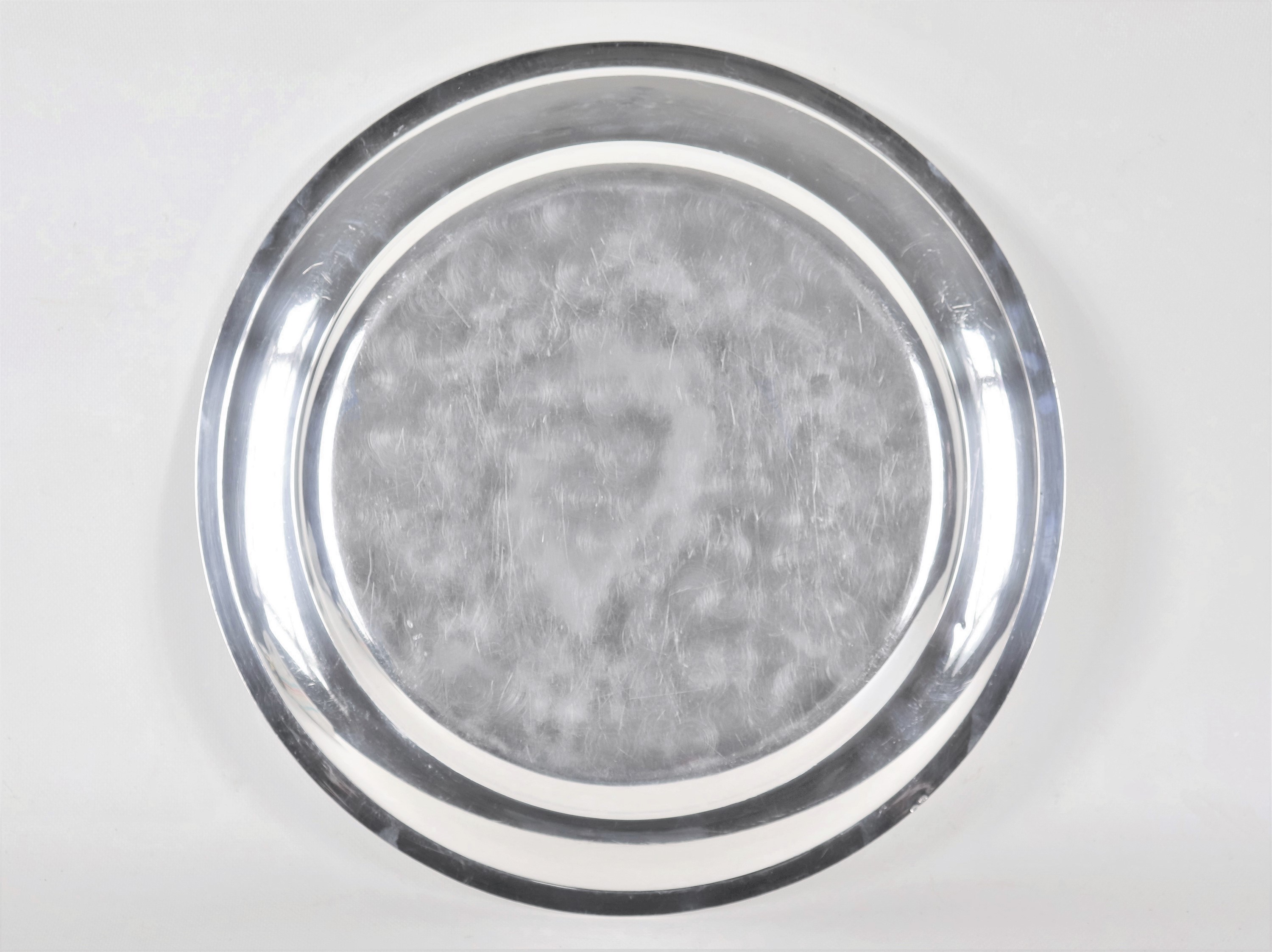 Grande piatto tondo da portata in argento, con bordo cesellato a palmette neoclassiche e monogram...