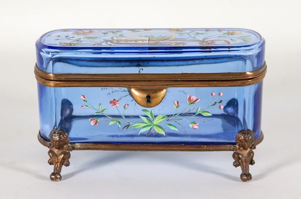 Scatola Liberty francese in cristallo celeste, con applicazioni di smalti a rilievo a motivi di fiori, foglie e fiocchi, sorretta da quattro piedini in bronzo