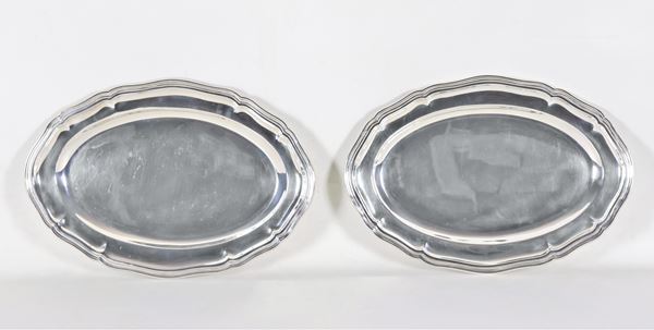 Coppia di grandi piatti ovali da portata in argento, con bordi centinati e sbalzati, gr. 2060