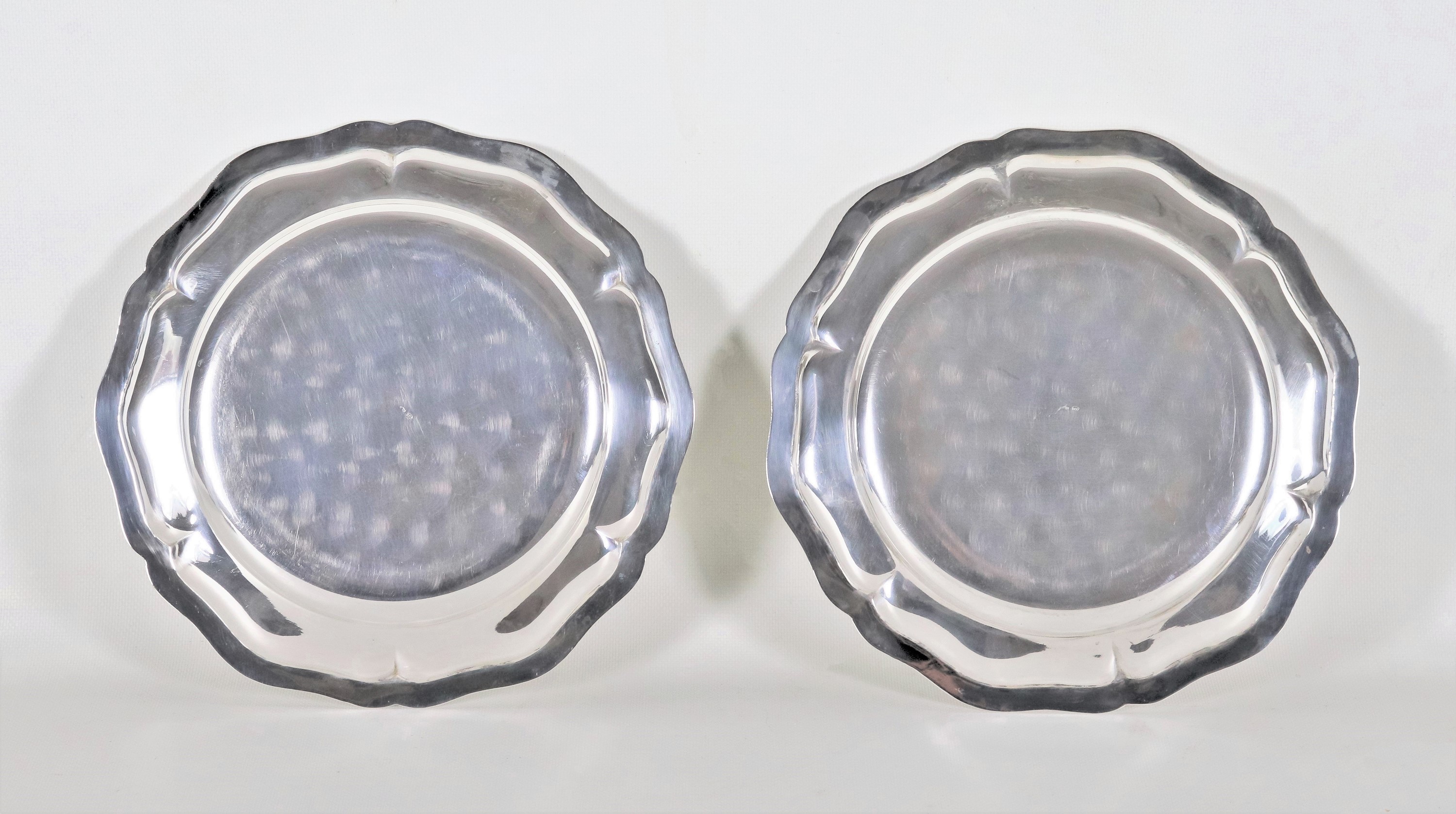 Coppia di piatti tondi in argento con bordo centinato e sbalzato, gr. 930