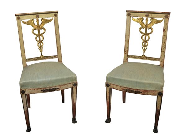Pair of First Empire chairs in gilded and ivory lacquered wood, with "The Caduceus of Mercury" in the center of the backs