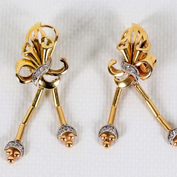 Coppia di orecchini a pendente in oro giallo 18kt, a motivo di foglia con serie di piccoli diamantini, gr. 13 circa