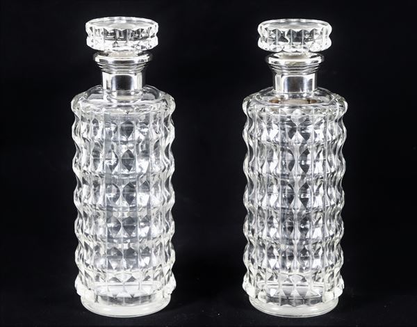 Coppia di bottiglie da liquore cilindriche in cristallo lavorato a rilievo, con colli rivestiti in argento
