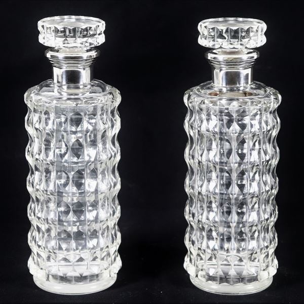 Pair of cylindrical liqueur bottles in relief-worked crystal, with silver-coated necks