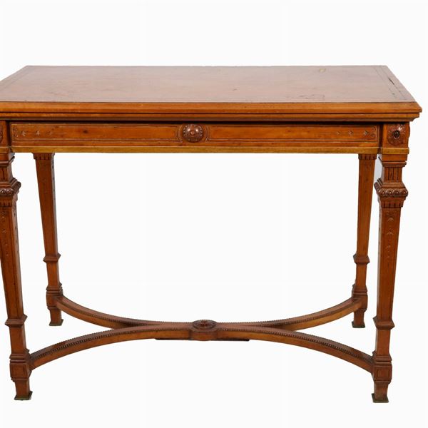 Antico tavolo da gioco inglese di linea Luigi XVI in legno di satinwood, con filettature e intagli a motivi di rosoni, piano girevole e ribaltabile con all'interno rivestimento in pelle verde con bordure dorate, quattro gambe a piramide riunite da crociera sagomata