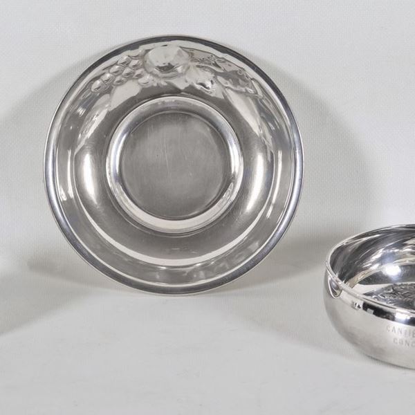 Lotto in argento di una coppetta assaggiavino, una ciotola tonda con grappolo d'uva sbalzato sul bordo e una ciotola tonda con bordo rialzato e fondo sbalzato (3 pz), gr. 350