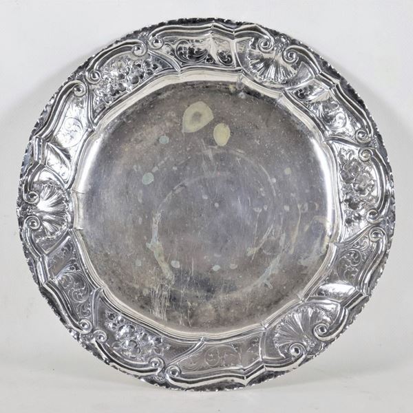 Antico piatto tondo in argento, con bordo cesellato e sbalzato a volute floreali e conchiglie, gr. 520
