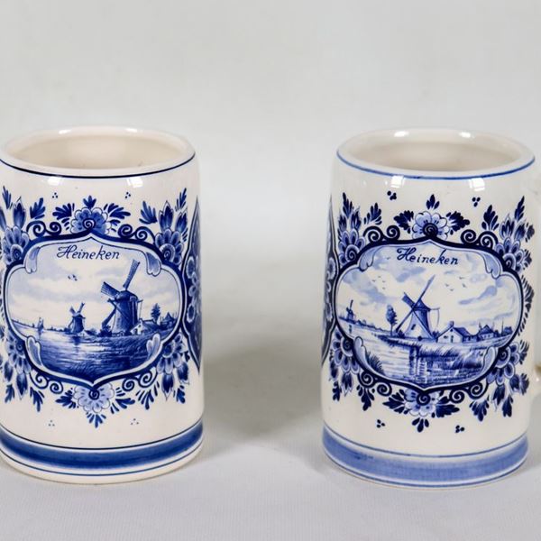 Pair of Dutch Delft porcelain beer mugs with blue decorations on a white background