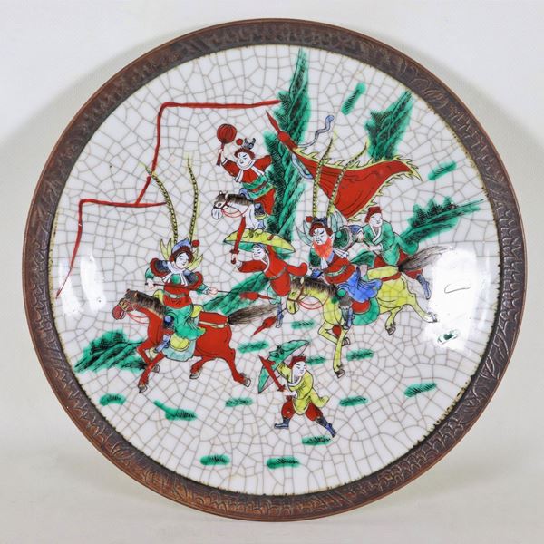 Chinese wall plate in porcelain with "Combat scene" in relief polychrome enamels, embossed metal border