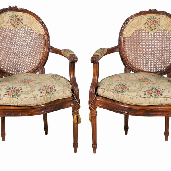 Coppia di antiche poltrone francesi in noce intagliate a motivi Luigi XVI, con schienali a medaglioni e gambe scannellate, copertura in canneté  con cuscini in tessuto fiorato