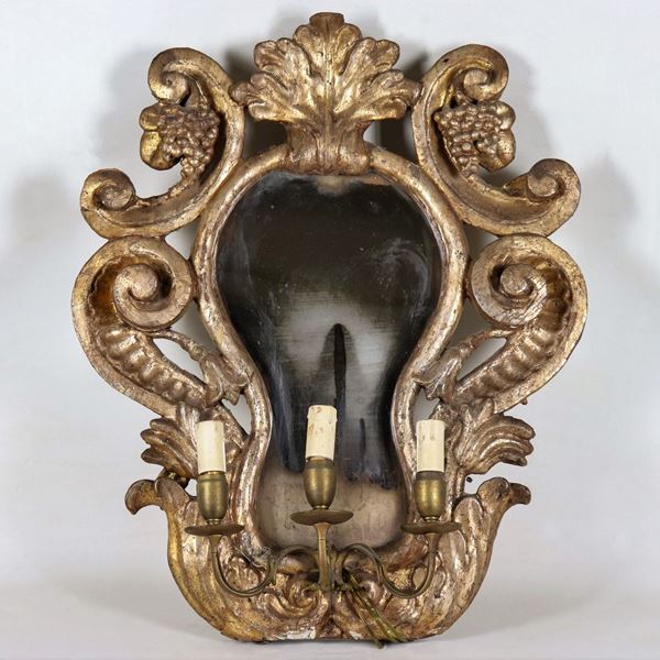 Ancient mirror in mecca-gilded wood and carved with motifs of curls, volutes and bunches of grapes, mercury mirror and electric light reduction with three lights