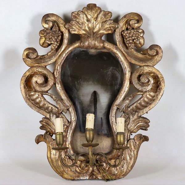 Ancient mirror in mecca-gilded wood and carved with motifs of curls, volutes and bunches of grapes, mercury mirror and electric light reduction with three lights