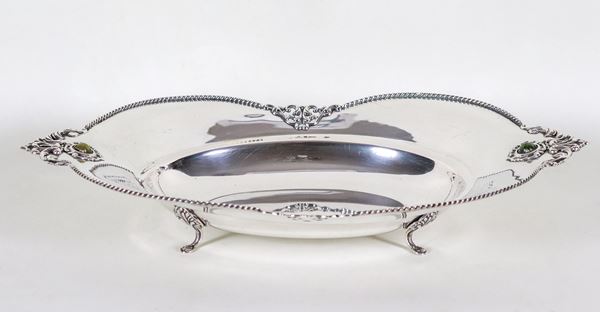 Centrotavola a forma sagomata in argento con bordo cesellato e sbalzato a volute e trafori, sorretto da quattro piedini ricurvi, gr. 460