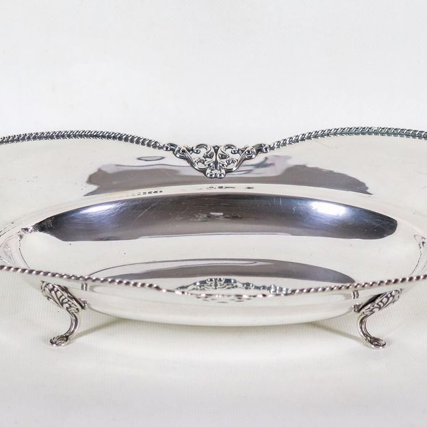 Centrotavola a forma sagomata in argento con bordo cesellato e sbalzato a volute e trafori, sorre...