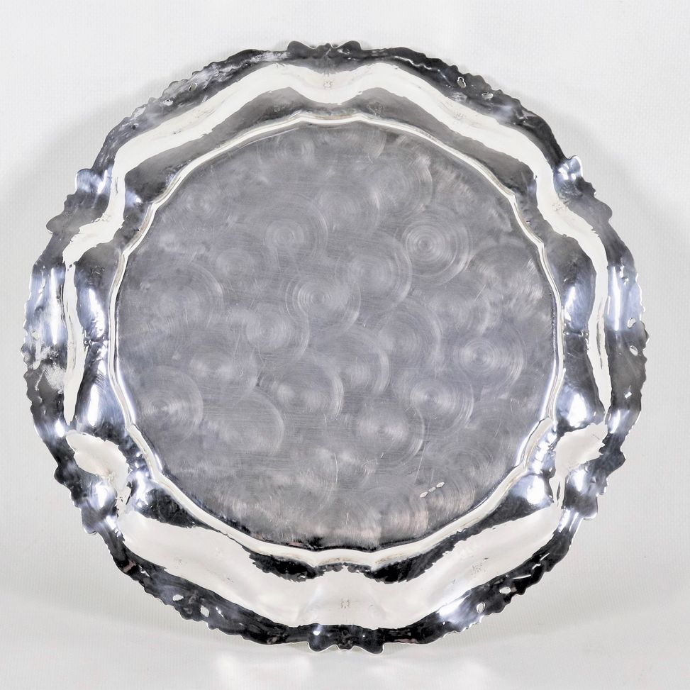 Piatto tondo in argento con bordo cesellato e sbalzato a volute, conchiglie e applicazioni di pie...