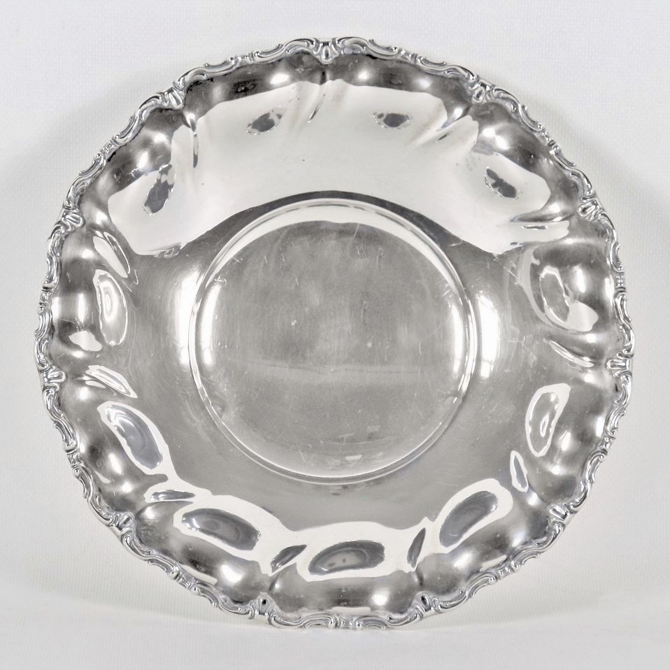 Piccolo centrotavola tondo in argento con bordo cesellato e sbalzato a volute, sorretto da tre pi...