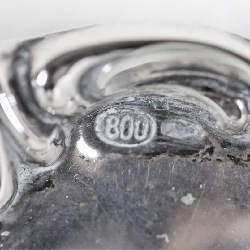 Piccolo centrotavola tondo in argento con bordo cesellato e sbalzato a volute, sorretto da tre pi...