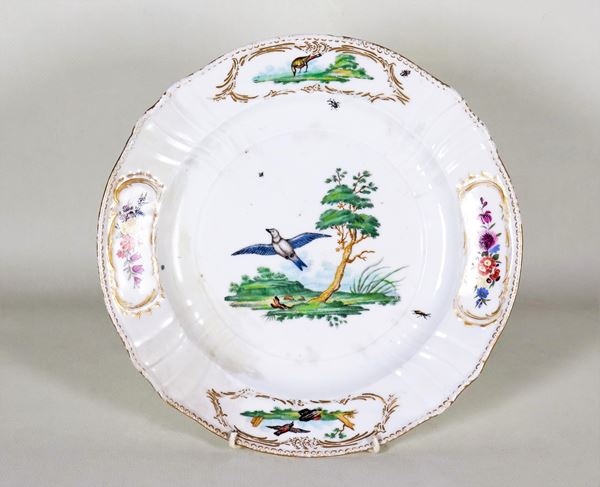 Antique white porcelain wall plate with painted decorations in relief with bird and flower motifs. The plate has defects and old restorations