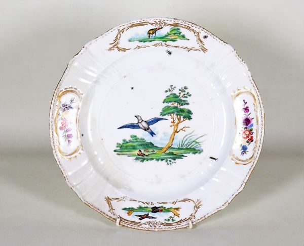 Antico piatto da muro in porcellana bianca con decorazioni dipinte a rilievo a motivi di uccelli e fiori. Il piatto presenta difetti e vecchi restauri