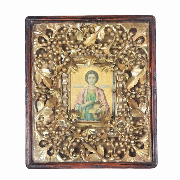 "San Pantaleimone", an ancient small travel icon painted on a tablet with a gold background, enclosed in a gilded copper frame with floral intertwining, bunches of grapes and stylized stars