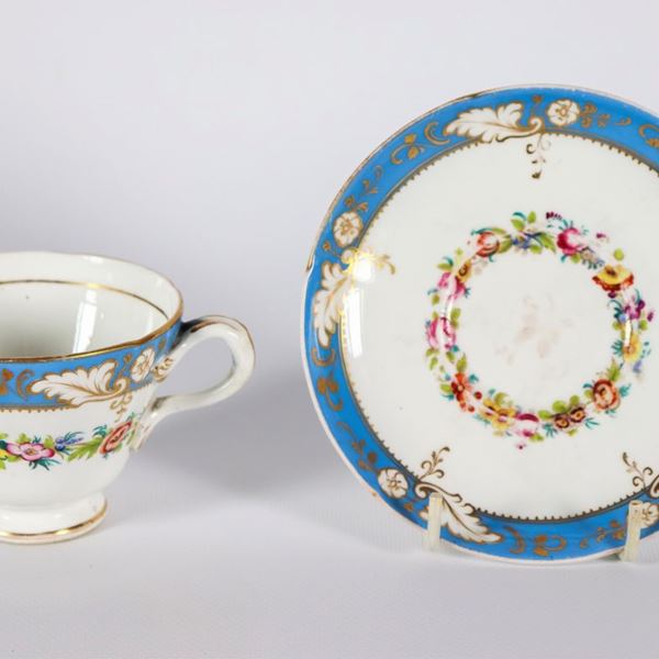 Cup and saucer in white and light blue French porcelain, with polychrome decorations with floral garlands and pure gold