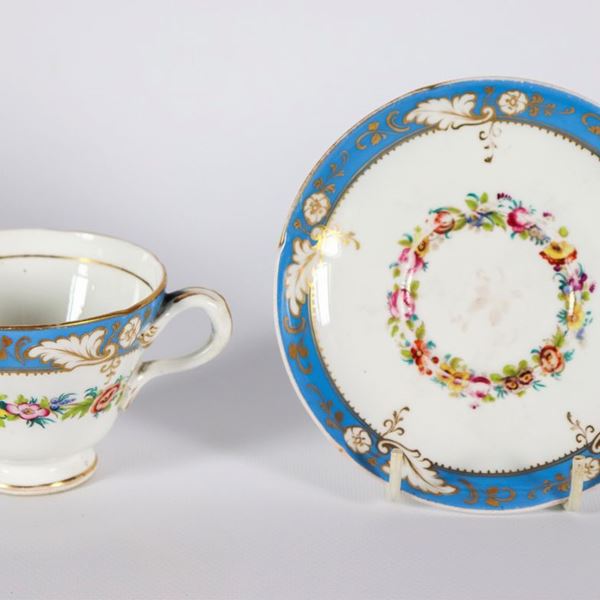 Tazza con piattino in porcellana francese bianca e celeste, con decorazioni policrome a ghirlande floreali e oro zecchino