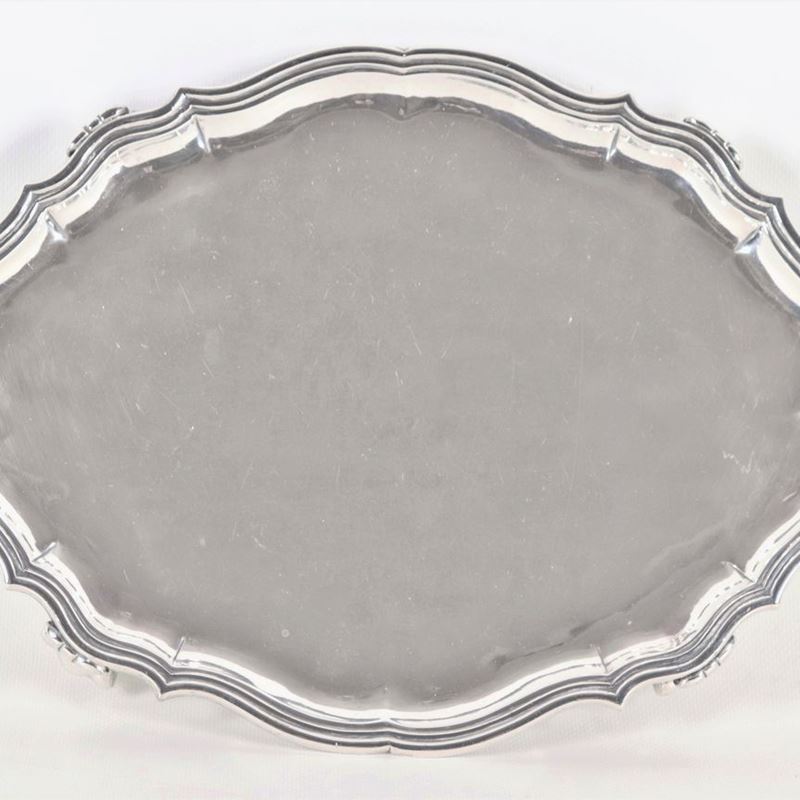 Antico vassoio ovale in argento con bordo centinato e sbalzato, sorretto da quattro piedini leoni...