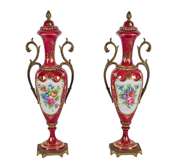Coppia di anfore francesi in porcellana rossa con decorazioni policrome a mazzetti di fiori e volute dorate, manici e basi in bronzo dorato