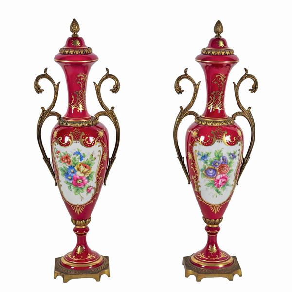 Coppia di anfore francesi in porcellana rossa con decorazioni policrome a mazzetti di fiori e volute dorate, manici e basi in bronzo dorato