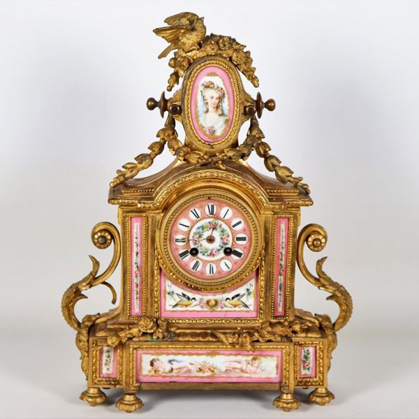 Ancient table clock in gilded, embossed and chiseled bronze with applications of Sèvres porcelain plates, decorated and colorful with motifs of "Ladies and allegories of cherubs", dial with Roman numerals