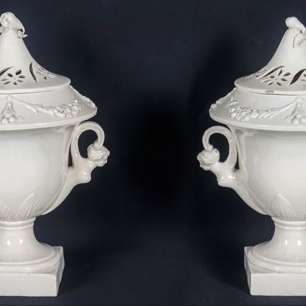 Coppia di vasi ad anfora in ceramica bianca smaltata e porcellanata, con ghirlande di frutta a rilievo e manici con figure muliebri