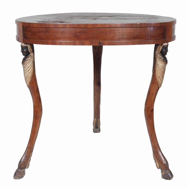 Tavolo da centro Impero in noce, a forma tonda con tre gambe dorate e intagliate con teste di sfingi, piano in legno molto danneggiato