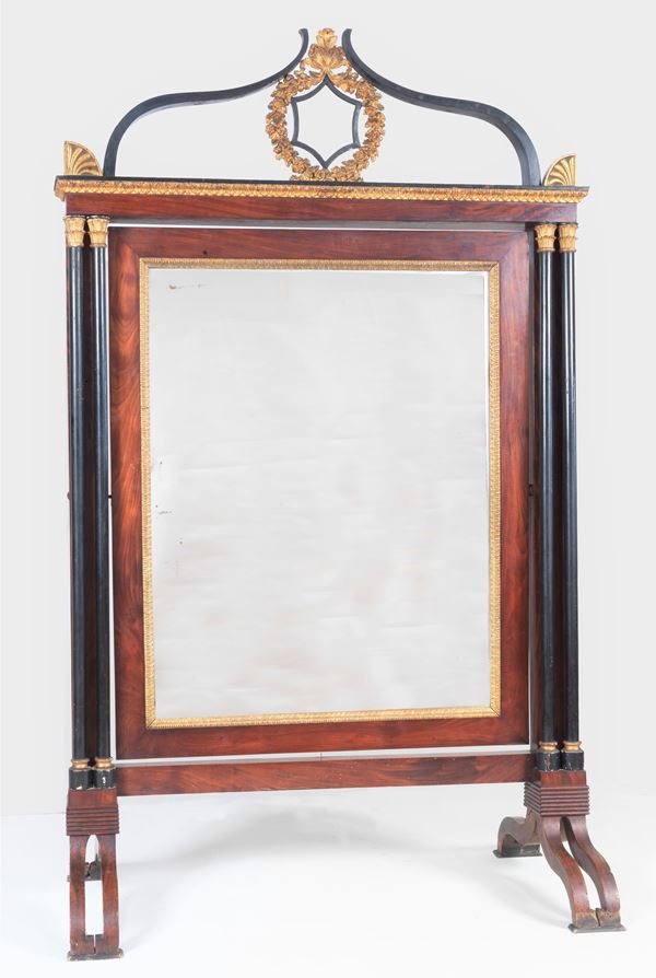 Large Emilian psyche First Empire (1804-1814) in mahogany, with uprights with ebonized columns and gilded capitals, cymatium with gilded laurel crown, tilting mirror and two arched legs