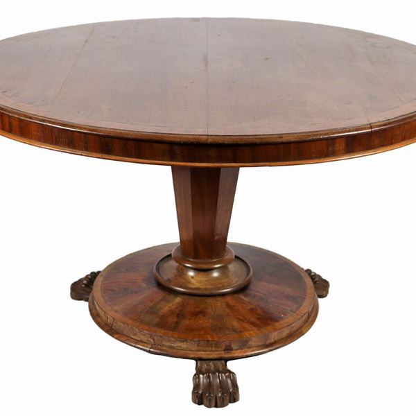 Tavolo tondo da pranzo inglese di linea Regency in noce, con fascia intarsiata sul piano in legno satinato, sorretto da base a colonna sfaccettata, poggiante su piano circolare con tre gambe leonine