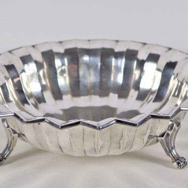 Fruttiera tonda in argento cesellato e sbalzato, con bordo smerlato e tre piedini ricurvi, gr. 395