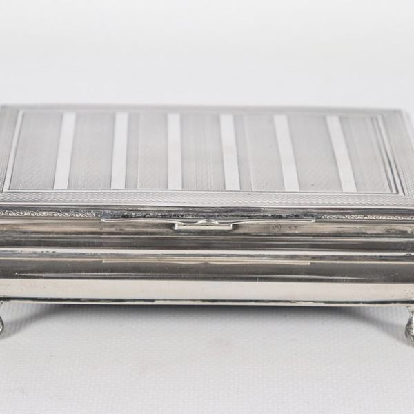 Rectangular cigarette box in silver, with chiselled lid and four leonine feet, gr. 210
