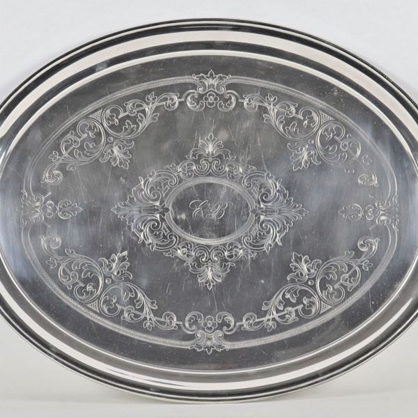 Grande vassoio ovale in metallo argentato, con fondo cesellato a volute floreali e monogramma centrale
