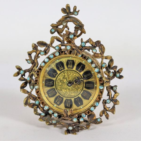 Small table alarm clock in gilded metal, embossed and chiseled with intertwining floral motifs, with applications of light blue enamel beads and dial with Roman numerals