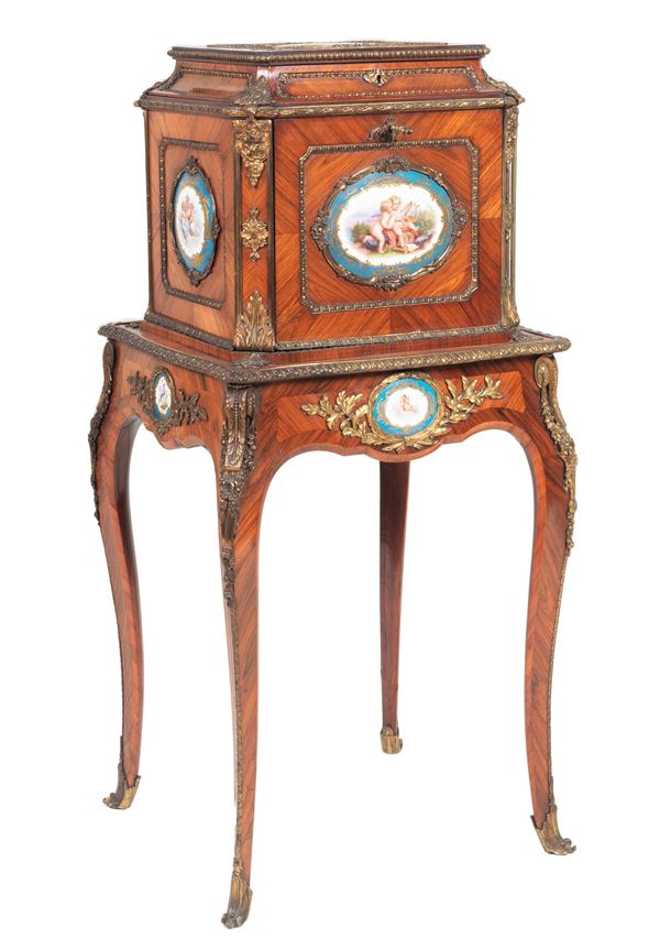French Napoleon III (1852-1870) centerpiece bonheur du jour in purple ebony, with applications of nine Sèvres porcelain plaques painted with scenes from "Allegories of putti", gilded and chiseled bronze trimmings and friezes, openable upper shelf, small flap forming a writing desk and four curved legs