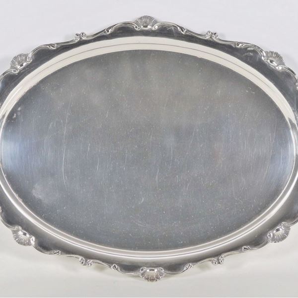 Curved oval tray in silver metal, with handles and edges chiseled and embossed with motifs of scrolls and shells