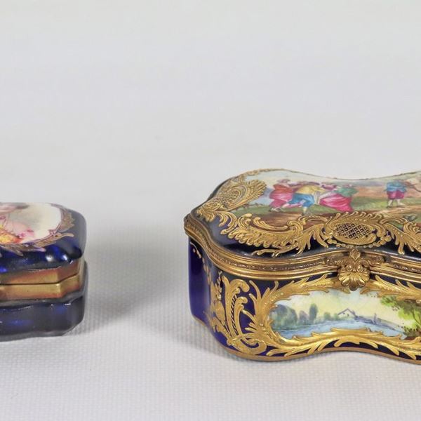 Lotto di una scatola e una tabacchiera in porcellana blu cobalto di Sèvres,la scatola di forma sagomata con scene dipinte di festa campestre e paesaggi, la tabacchiera con medaglione dipinto sul coperchio con ritratto di giovane dama. La scatola è della Metà del XVIII Secolo