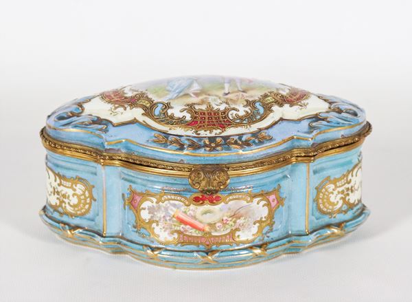Oval box in light blue Sèvres porcelain, with relief highlights in pure gold and painted squares with intertwining floral motifs and arch with quiver, painted scene signed "The courtship" on the lid