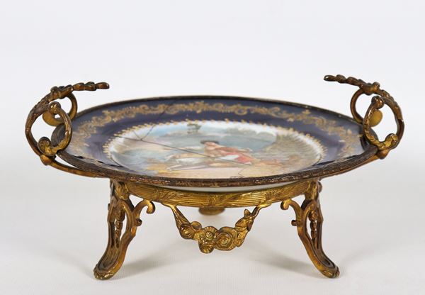 Round wing in Sèvres porcelain, with cobalt blue and pure gold border, in the center painted scene signed "Mother with little son", handles and base in gilded and chiselled bronze. Breakups