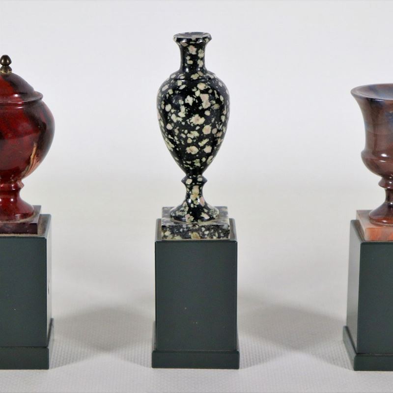 Lotto di tre modellini di vasi e anfore a vari marmi policromi, sorretti da basette quadrangolari