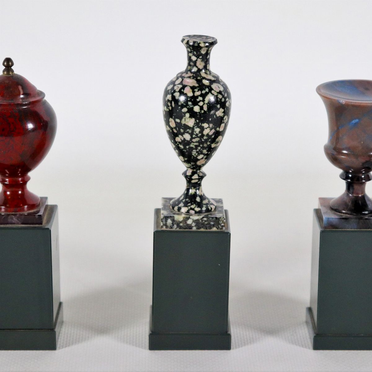 Lotto di tre modellini di vasi e anfore a vari marmi policromi, sorretti da basette quadrangolari