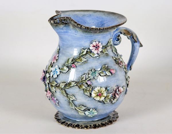 Brocca Liberty in ceramica smaltata celeste, con decorazioni a rilievo a motivi di intrecci floreali, lievi difetti