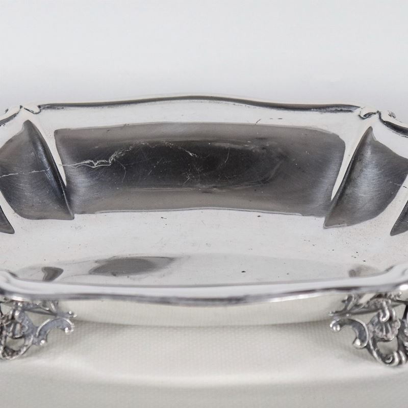 Piccolo centrotavola ovale in argento con bordo centinato, sorretto da quattro piedini sbalzati, ...
