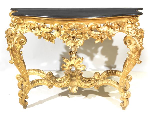 Antique Neapolitan Louis Philippe console (1830-1848), in gilded wood and carved with motifs of acanthus leaves, curls and flowers, four curved legs joined by a shaped cross and black marble top