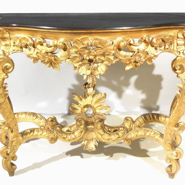Antica consolle napoletana Luigi Filippo (1830-1848), in legno dorato e intagliato a motivi di foglie d'acanto, ricci e fiori, quattro gambe ricurve riunite da crociera sagomata e piano in marmo nero